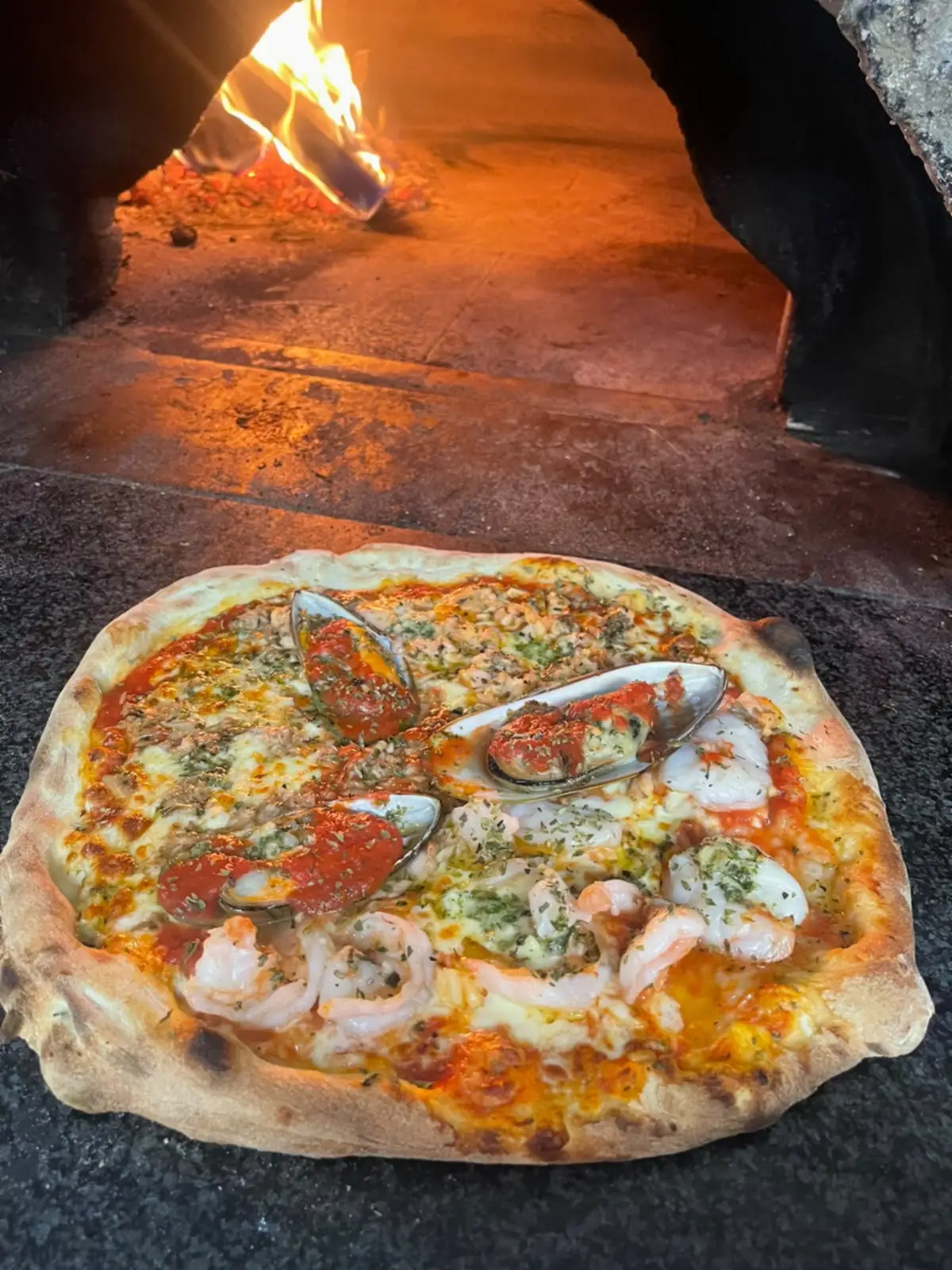 Une pizza aux fruits de mer, moules et crevettes, sur la pierre du four.